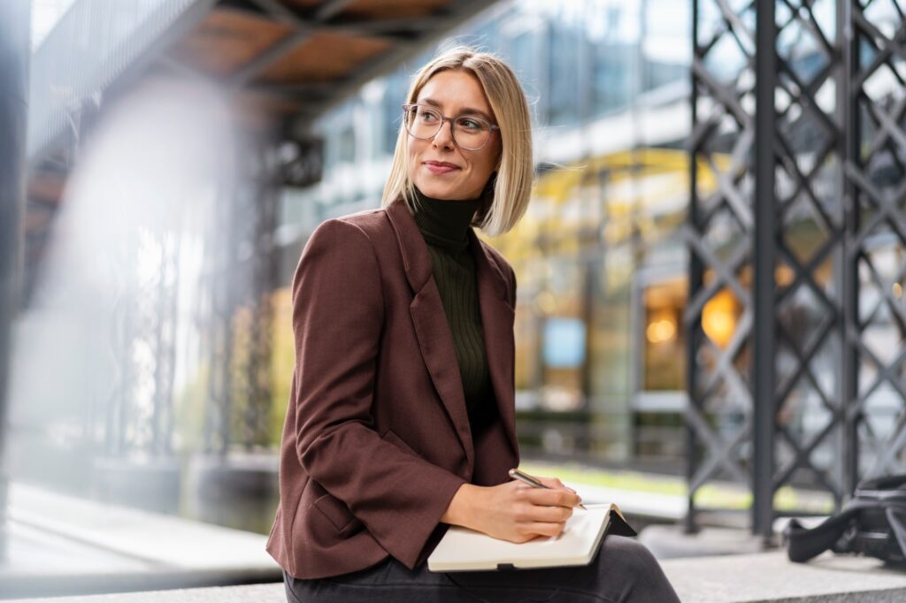 Smiling young businesswoman with notebook in the city